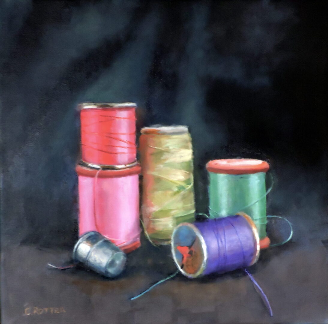 Colorful sewing threads and spools on a dark surface.